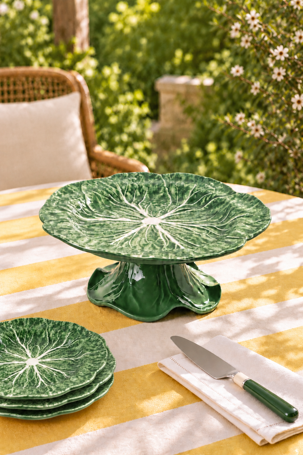 Green cabbage melamine cake stand with matching green side plates and cake knife on a striped garden table
