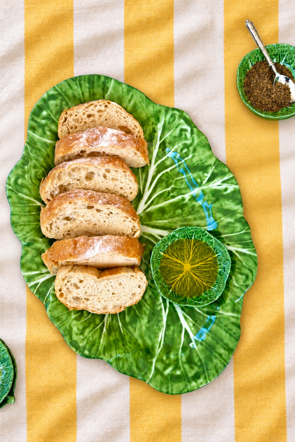 Green XL Oval Platter – Cabbage Melamine styled with bread and oil on yellow and white striped tablecloth