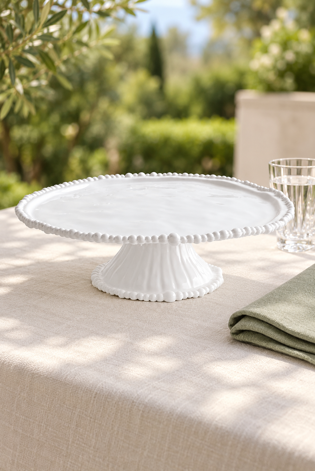 White Pearl Melamine cake stand, empty, styled outdoors with green linen