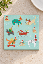 Holiday Dogs Paper Napkins in a precisely aligned thin paper stack, viewed overhead on a pale stone bench; Coast to Coast XM2408